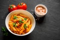 Pasta Penne in tomato sauce Pomodoro, garnished green basil leaves on black table. Traditional italian food. Top view Royalty Free Stock Photo