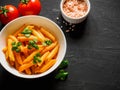 Pasta Penne in tomato sauce Pomodoro, garnished green basil leaves on black table. Traditional italian food. Top view Royalty Free Stock Photo