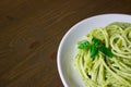 Pasta with pesto sauce and basil leafs on white plate, wood background, top view Royalty Free Stock Photo