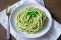 Pasta with pesto sauce and basil leafs on white plate, wood background, top view Royalty Free Stock Photo