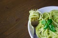 Pasta with pesto sauce and basil leafs on white plate, wood background, top view Royalty Free Stock Photo