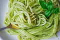 Pasta with pesto sauce and basil leafs on white plate, wood background, top view Royalty Free Stock Photo