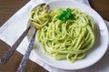 Pasta with pesto sauce and basil leafs on white plate, wood background, top view Royalty Free Stock Photo