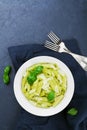 Pasta with pesto sauce decorated basil leaves and parmesan cheese in white dish on blue table from above. Royalty Free Stock Photo
