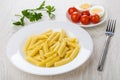 Pasta in plate, fork, tomatoes, boiled eggs in saucer, parsley Royalty Free Stock Photo