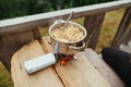 Pasta is prepared in a pan on a burner while traveling on a wooden table in the mountains