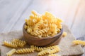 Pasta raw macaroni on wooden bowl background, close up raw macaroni spiral pasta uncooked delicious fusilli pasta for cooking food Royalty Free Stock Photo