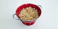 Pasta and red colander on plain background Royalty Free Stock Photo
