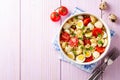 Pasta salad with quail eggs, mozzarella, cherry tomatoes and capers in bowl on purple wooden background Royalty Free Stock Photo