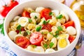 Pasta salad with quail eggs, mozzarella, cherry tomatoes and capers in bowl on purple wooden background Royalty Free Stock Photo