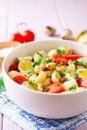 Pasta salad with quail eggs, mozzarella, cherry tomatoes and capers in bowl on purple wooden background Royalty Free Stock Photo