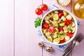 Pasta salad with quail eggs, mozzarella, cherry tomatoes and capers in bowl on purple wooden background Royalty Free Stock Photo