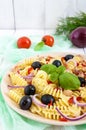 Pasta salad radiatori with chicken, black olives, blue onion, sweet pepper on a white wooden background.