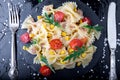 Pasta salad in slate plate with tomatoes cherry, tuna, corn and arugula near knife and spoon. Top view. ingredients. Italian food.