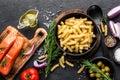 Pasta, salmon fish and ingredients for cooking on black background, top view. Italian food