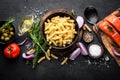 Pasta, salmon fish and ingredients for cooking on black background, top view. Italian food