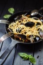 Pasta with seafood. Rustic style spaghetti with mussels in cast iron pan on black background Royalty Free Stock Photo