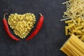 Pasta in the shape of a heart on a black background. With red hot chili peppers. Royalty Free Stock Photo