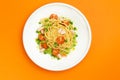 Pasta with shrimp and tomato in a plate on an orange background. Royalty Free Stock Photo