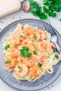 Pasta with shrimps in creamy parmesan cheese and garlic sauce garnished with parsley, fettucini alfredo, vertical, top view,