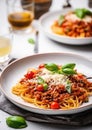 Pasta spaghetti bolognese with minced beef sauce, tomatoes, parmesan cheese and fresh basil in a plate on white table. Royalty Free Stock Photo