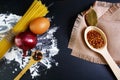 Pasta spaghetti, italian foods concept and menu design, spices on wooden spoons, onion bay leaf, raw eggs and flour on a shale boa Royalty Free Stock Photo