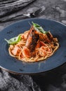 Pasta spaghetti with seafood, langoustine, mussels, oysters, shrimp, salmon fillet in sauce with herbs in plate over dark grey Royalty Free Stock Photo