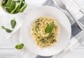 Pasta with spinach and cheese on a plate, fork, fresh spinach leaves, top view