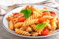 Pasta spirali stirred with fried pieces of chicken, cherry tomatoes