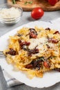 Pasta with sun dried tomatoes and parmesan in a white plate on the table. Italian food dish, vertical image