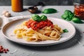 Pasta Tagliatelle Bolognese with meat tomato sauce and fresh basil leaves on white plate. Light gray table. Selective focus.