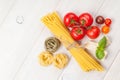 Pasta, tomatoes, basil on wooden table Royalty Free Stock Photo