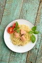 Pasta with tomatoes, green basil and salmon filet in white plate
