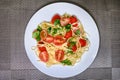 Pasta with tomatoes. Plate with spaghetti and cherry tomatoes on the table. Pasta decorated with leaves of parsley and cilantro