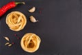 Pasta Top view. Fettuccine nests on a gray background with spices: hot peppers, fennel seeds and chilli peppers. Flat lay