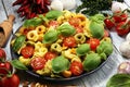 Pasta. tricolor tortellini pasta salad with tomatoes and onions on wood table background Royalty Free Stock Photo