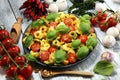 Pasta. tricolor tortellini pasta salad with tomatoes and onions on wood table background Royalty Free Stock Photo