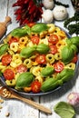 Pasta. tricolor tortellini pasta salad with tomatoes and onions on wood table background Royalty Free Stock Photo