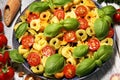 Pasta. tricolor tortellini pasta salad with tomatoes and onions on wood table background Royalty Free Stock Photo