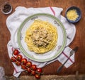 Pasta with turkey in cream sauce, cheese, cherry tomatoes on a branch, on a white plate on a napkin on wooden rustic background to Royalty Free Stock Photo