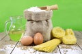 Pasta, Two Eggs, Jute Bag Filled with Flour, Wooden Spoon and Olive Oil in Glass Bottle on an Old Wooden Table