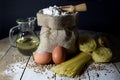 Pasta, Two Eggs, Jute Bag Filled with Flour, Wooden Spoon and Olive Oil in Glass Bottle on Wooden Table, Black Background