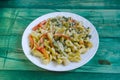 Pasta with vegetables and cheese in a white plate on a green background Royalty Free Stock Photo