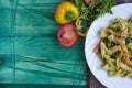 Pasta with vegetables and cheese in a white plate on a green background Royalty Free Stock Photo