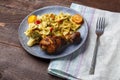 Pasta with vegetables and cherry tomatoes with baked chicken leg on the table next to a light napkin and fork. Royalty Free Stock Photo