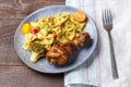 Pasta with vegetables and cherry tomatoes with baked chicken leg on the table next to a light napkin and fork. Royalty Free Stock Photo