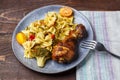 Pasta with vegetables and cherry tomatoes next to a baked chicken leg on the table next to a light napkin and a fork. Royalty Free Stock Photo