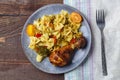 Pasta with vegetables and cherry tomatoes next to a baked chicken leg on the table next to a light napkin and a fork. Royalty Free Stock Photo