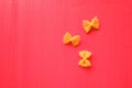 Pasta yellow bows on bright pink wooden background