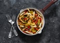 Pasta, zucchini, mushrooms, sweet paprika vegetable stewed tomato sauce in a pan on a dark background, top view. Vegetarian food